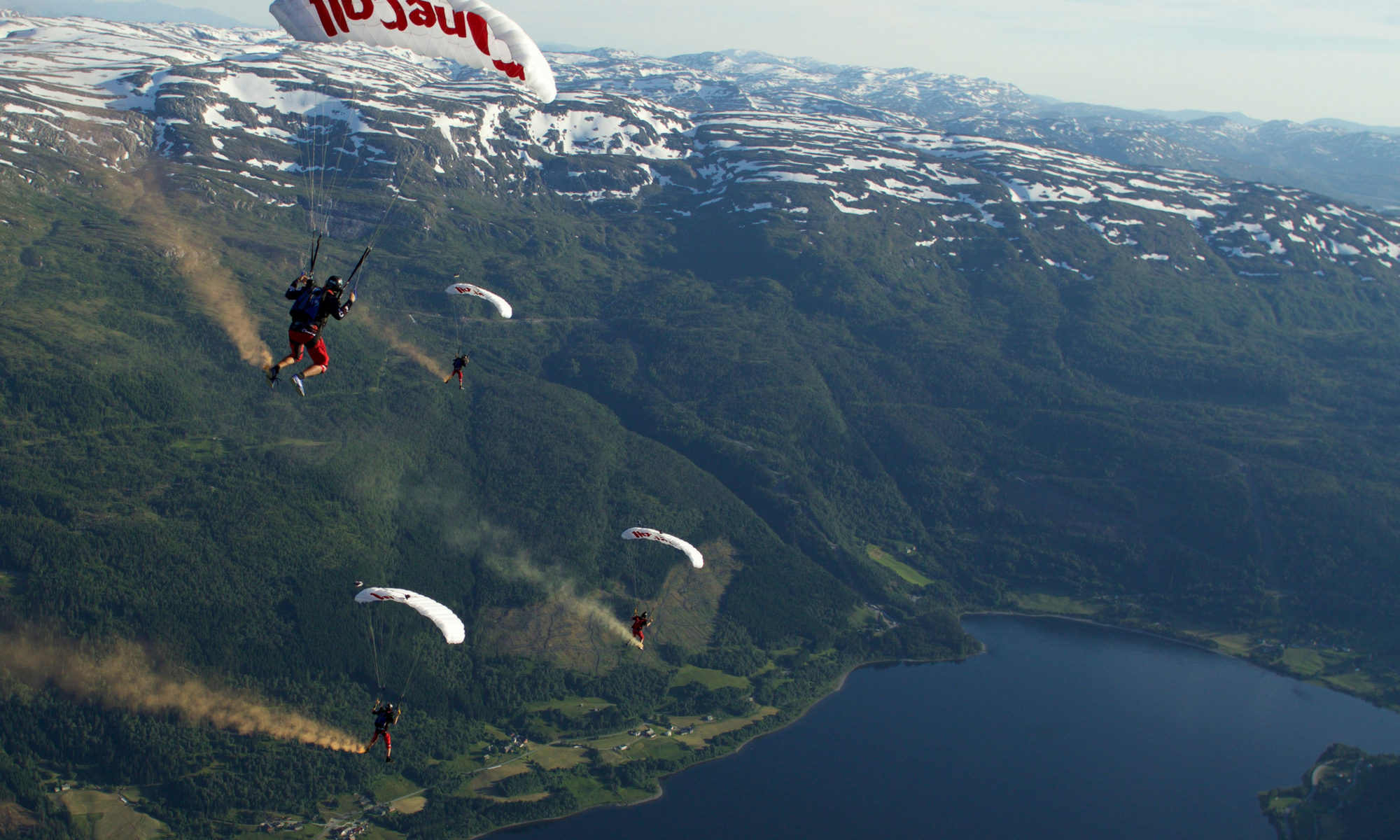 Shannon Pilcher under canopy with PD Factory team with a view of snowy mountains and beautiful lake